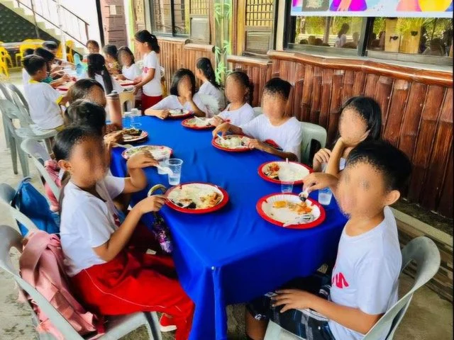 Children sharing a meal in the Ako Ang Saklay feeding program; faces are blurred for privacy