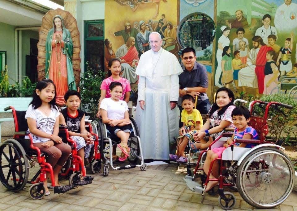 Children, including some using wheelchairs, posing with Pope Francis and Fr. Arnold Abelardo